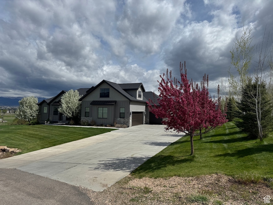 View of front of property featuring driveway, a front lawn, and stone siding