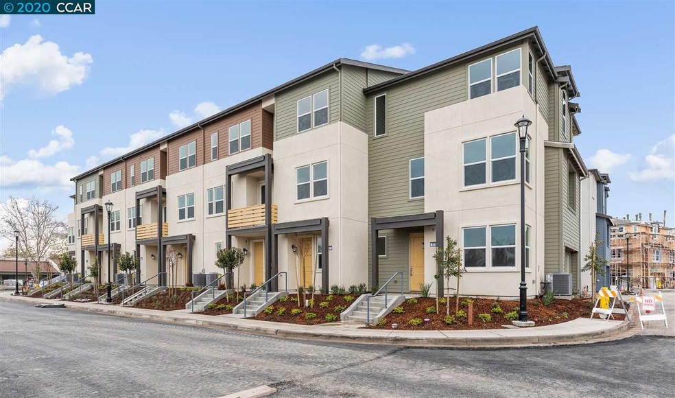 Exterior photo of completed building within the community, home still under construction.