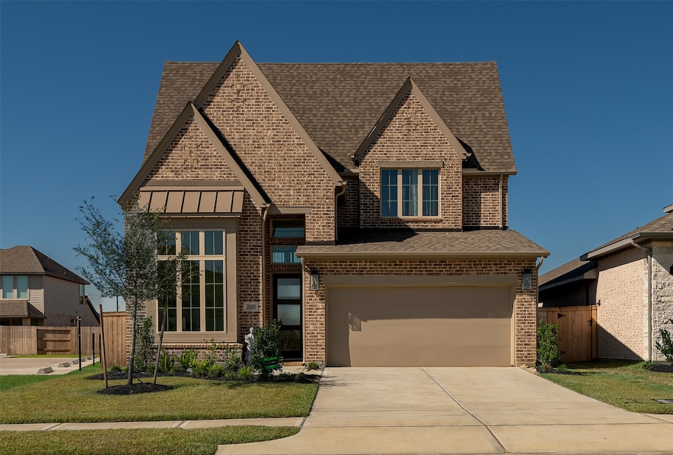 This charming two-story brick home features a gabled roof and a two-car garage. The well-maintained front yard includes a small tree and neatly arranged shrubs. Ideal for family living in a suburban neighborhood.