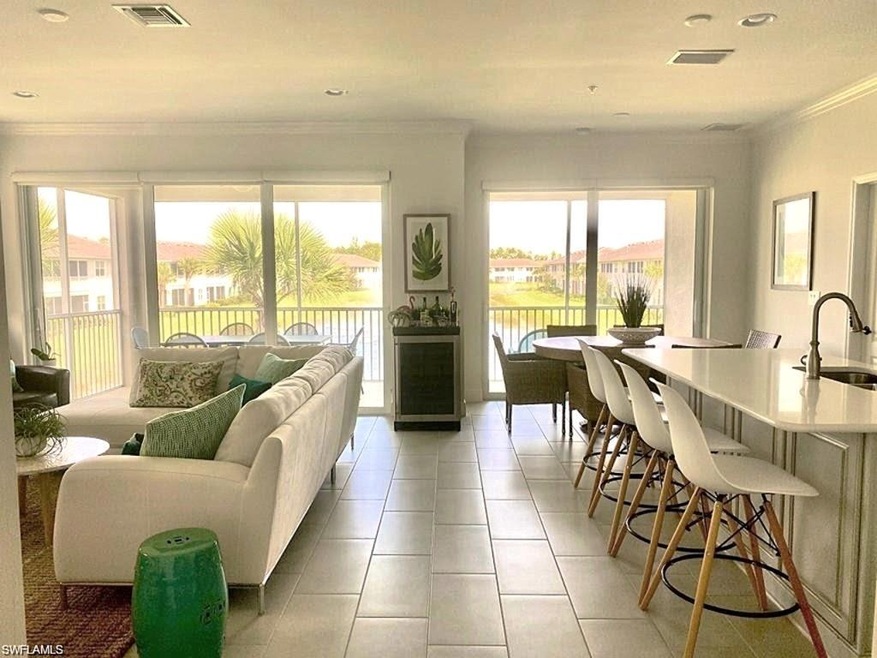 Living room with ornamental molding, a water view, sink, and light tile patterned flooring