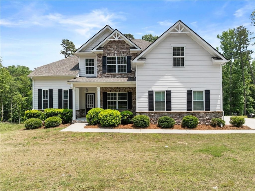 Craftsman-style house featuring stone siding, a front lawn, and roof with shingles