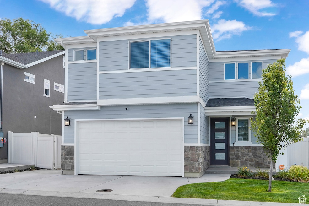 View of front of property featuring stone siding, concrete driveway, and a garage