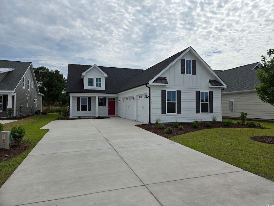View of front of home with board and batten siding, a garage, driveway, and a front yard