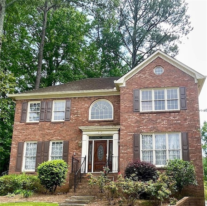 Colonial-style house featuring brick siding and a shingled roof