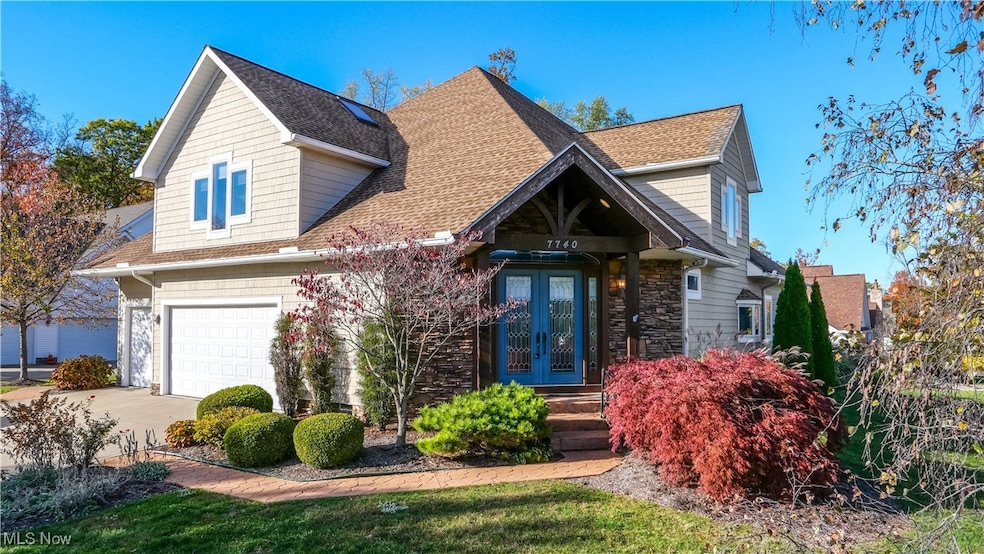 View of front of home with a shingled roof, driveway, a garage, french doors, and stone siding