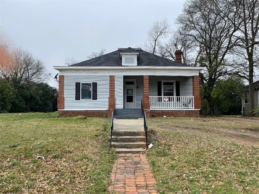 Bungalow with a chimney, covered porch, and a front lawn