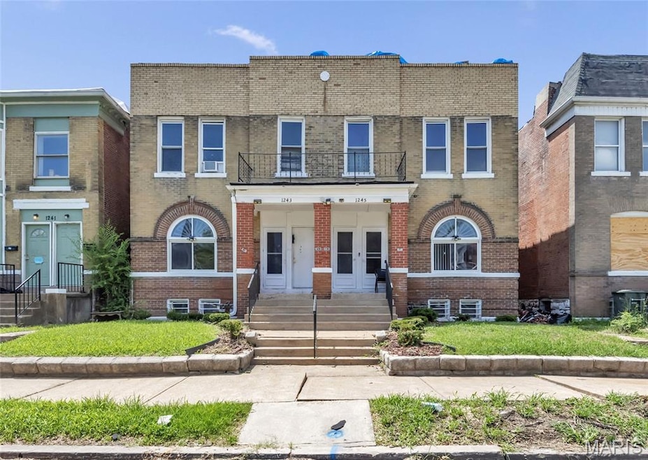 View of front of home featuring french doors, brick siding, and a balcony