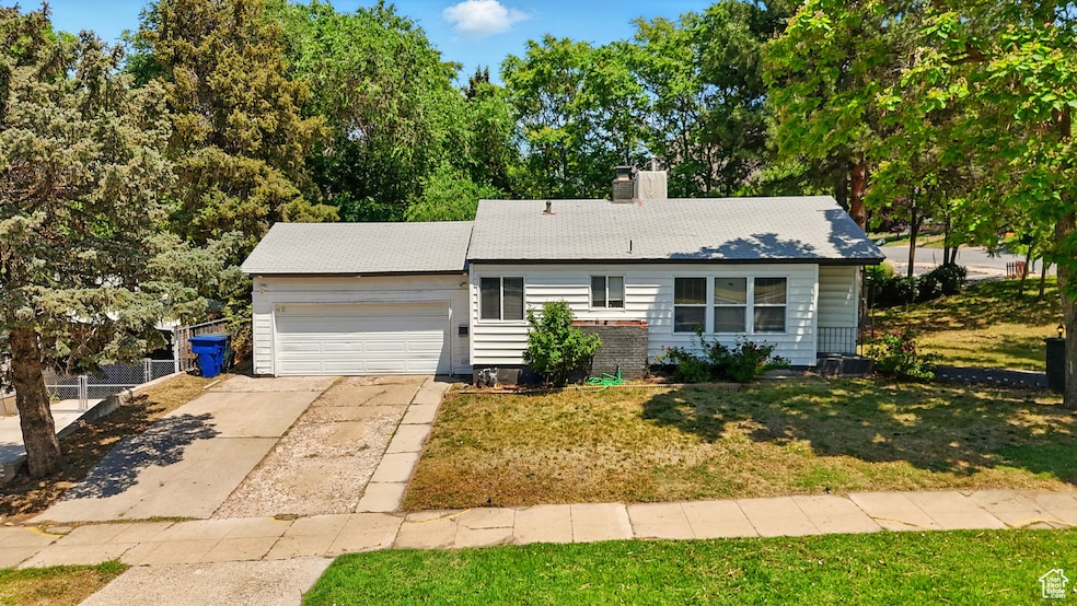 Ranch-style house featuring a garage, driveway, and a chimney