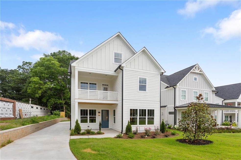 Modern farmhouse style home with board and batten siding, a balcony, a front yard, and concrete driveway