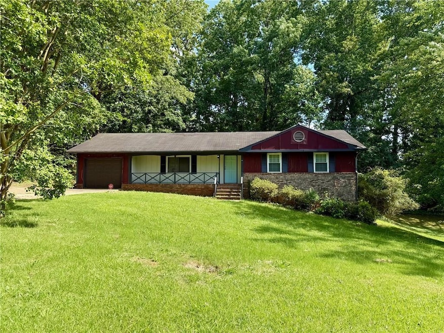 Ranch-style home featuring a garage, a front yard, driveway, a porch, and stone siding