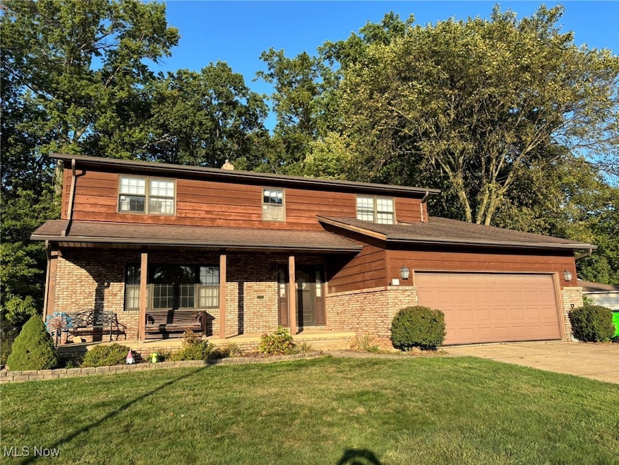 View of front of property with a front yard, driveway, an attached garage, and a porch