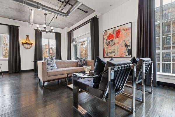Living room featuring baseboards, a notable chandelier, and dark wood finished floors