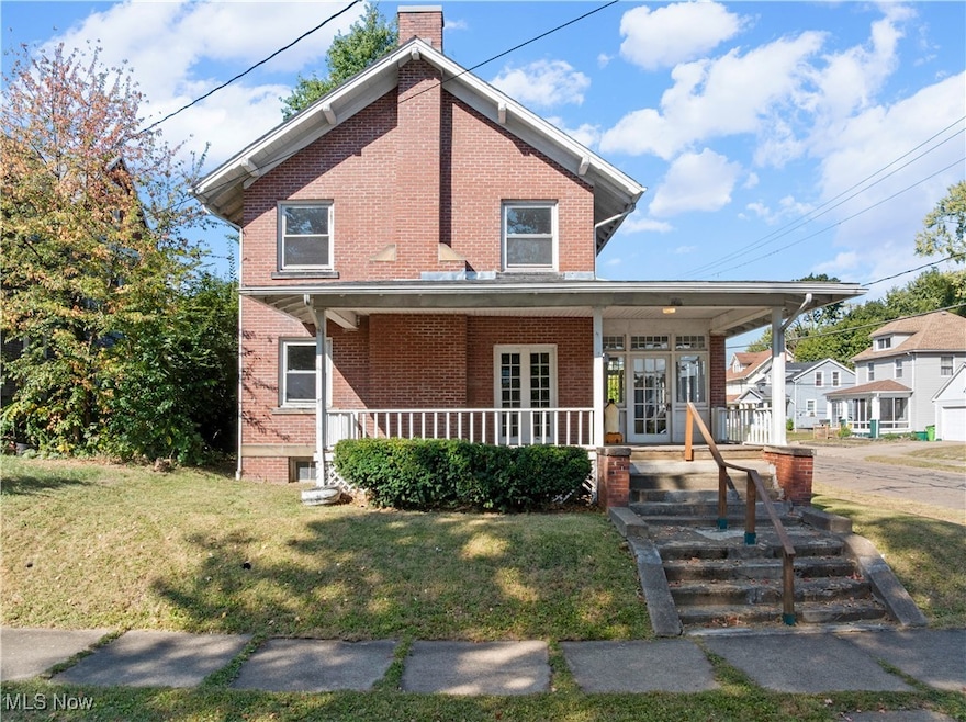 View of front facade featuring a porch, a chimney, and a front lawn