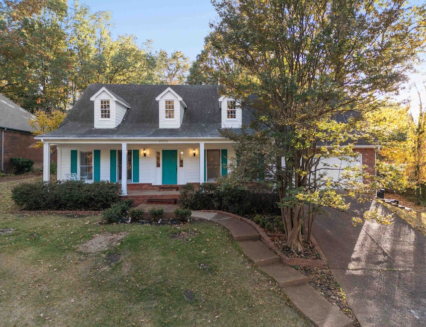 New england style home featuring a front yard, covered porch, a garage, roof with shingles, and driveway