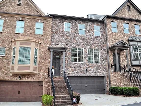 Multi unit property with concrete driveway, an attached garage, and brick siding