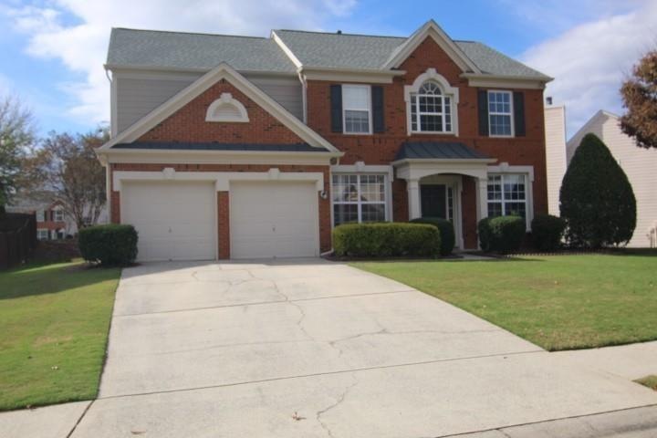 Colonial-style house with a garage, driveway, and a front lawn