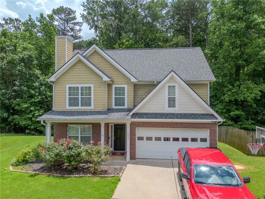 Traditional-style home with roof with shingles, driveway, a chimney, and brick siding