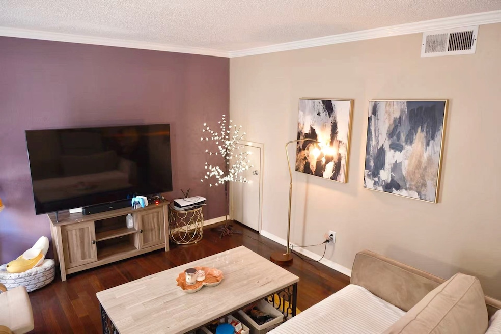 Living area with ornamental molding, dark wood-type flooring, and a textured ceiling