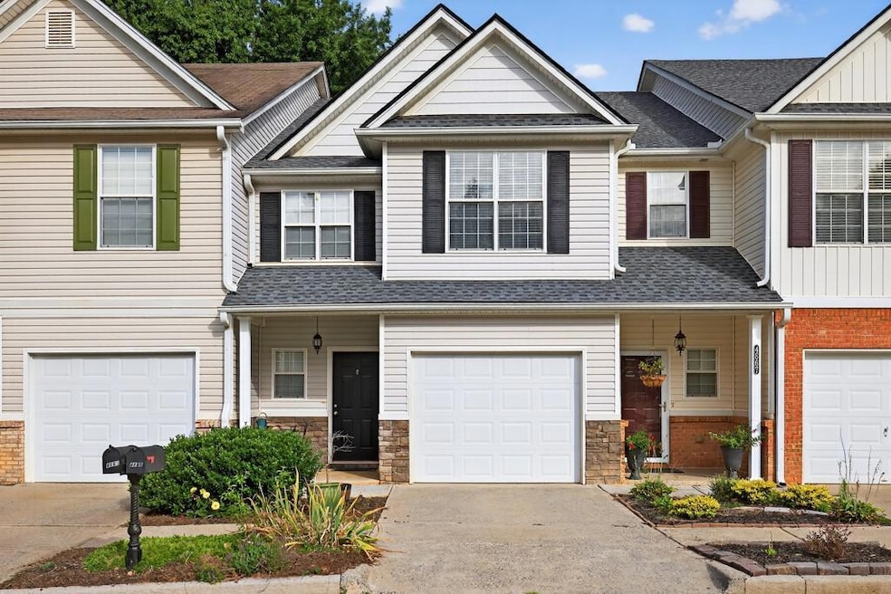 View of front facade featuring driveway, covered porch, and roof with shingles