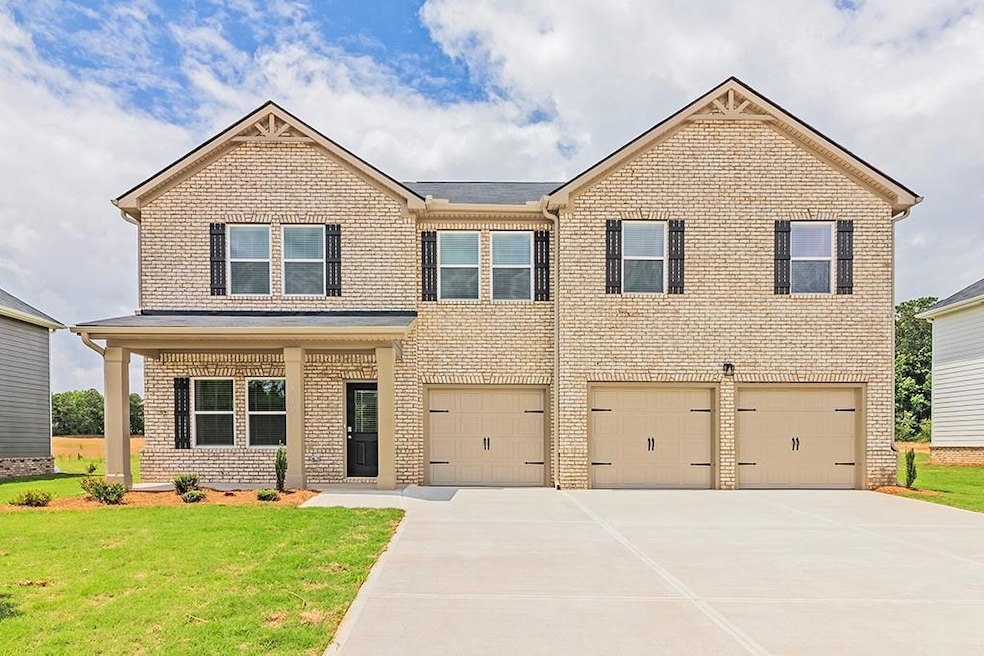 View of front of house featuring brick siding, a garage, driveway, and a front lawn