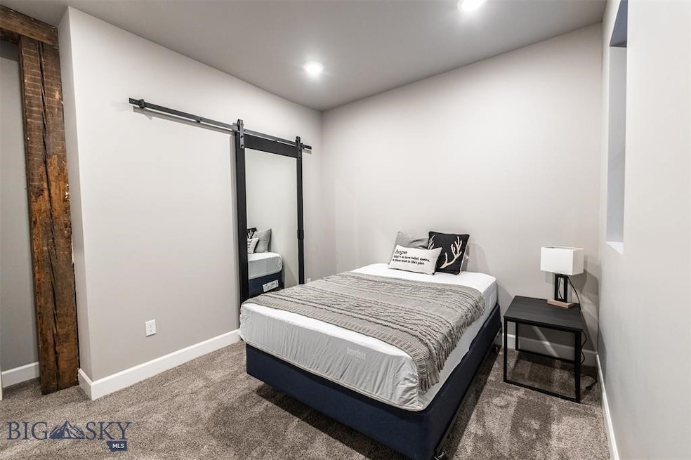 Bedroom featuring a barn door and dark carpet