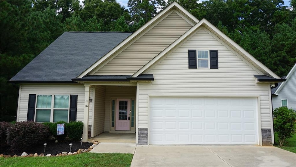Traditional home with driveway, a garage, stone siding, and roof with shingles