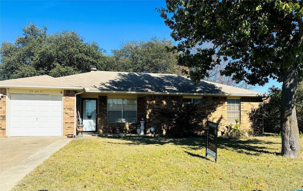 Ranch-style house featuring an attached garage, a front yard, driveway, and brick siding