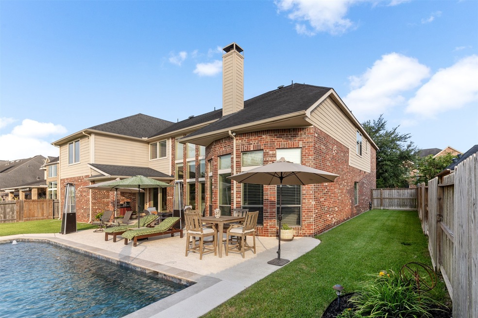 Private backyard with expansive patio, pool and lush green grass.