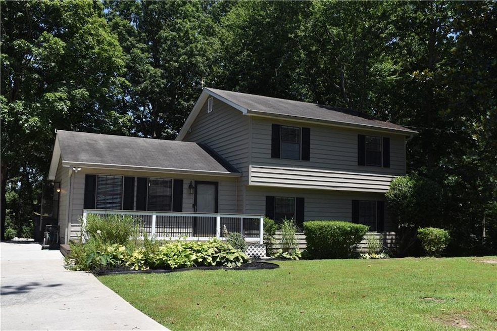 Tri-level home featuring a front lawn, a porch, and concrete driveway