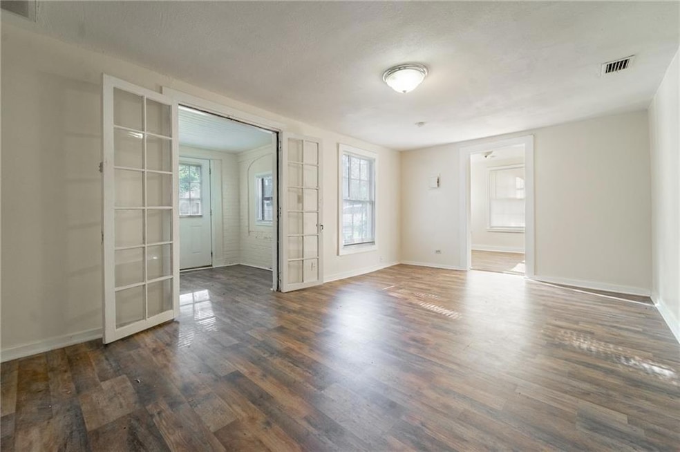 Empty room featuring healthy amount of natural light, dark wood-style floors, and french doors