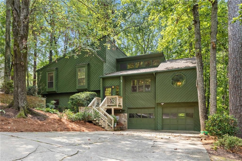 View of front of property featuring stairs, a garage, and concrete driveway