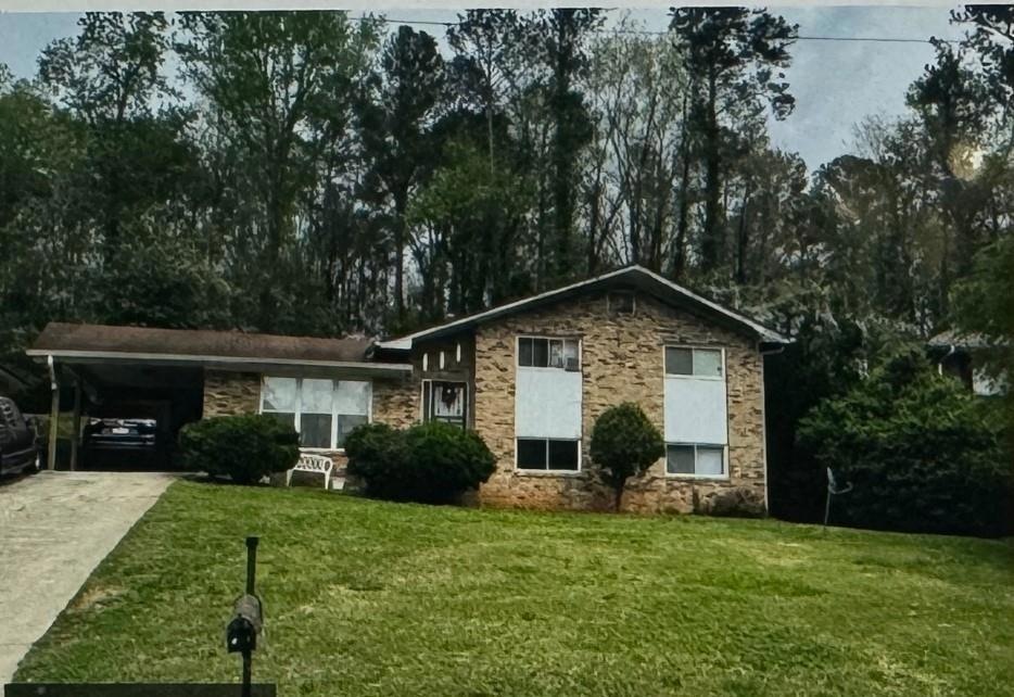 Split level home with a front lawn and a carport