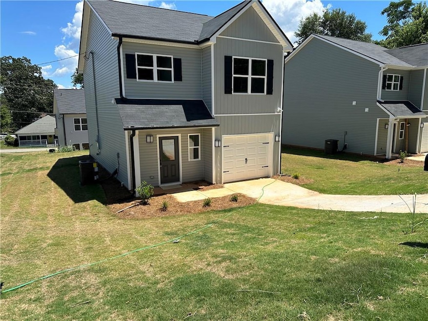 View of front of property featuring driveway, a garage, a front yard, and a shingled roof