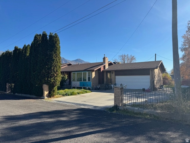 Ranch-style home with an attached garage, driveway, and a chimney