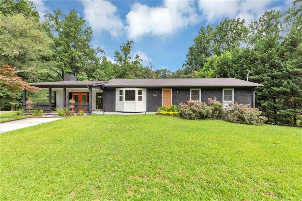 View of front of house featuring a front lawn, french doors, a chimney, and concrete driveway
