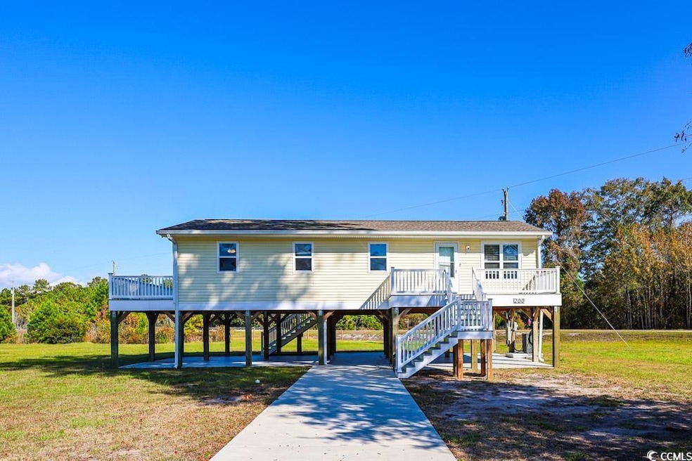View of front of house featuring a front yard, a carport, a wooden deck, and stairs