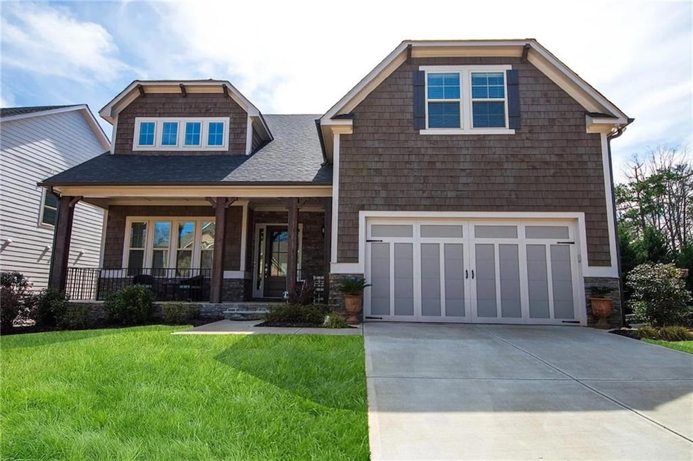 Craftsman-style home with a front lawn, driveway, a porch, a garage, and a shingled roof