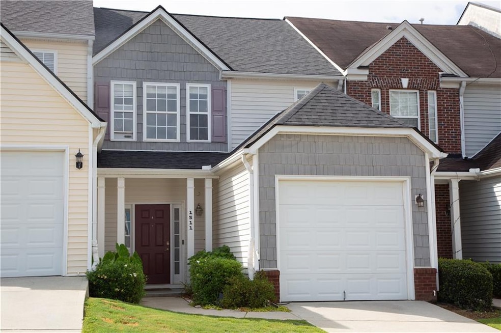 Traditional home featuring an attached garage, roof with shingles, and concrete driveway