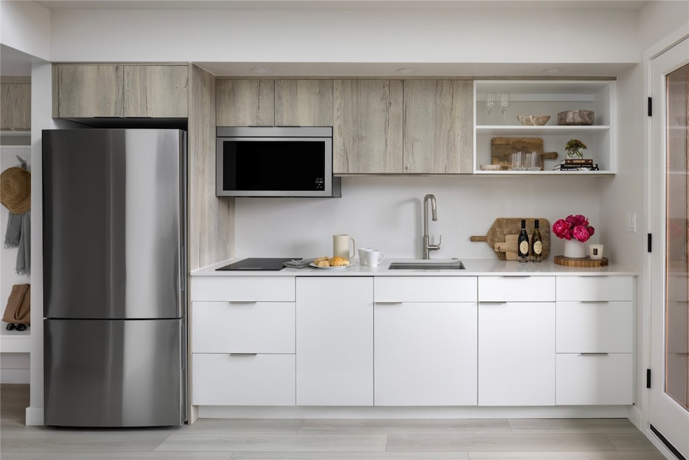 Kitchen featuring modern cabinets, stainless steel appliances, open shelves, light wood-style floors, and white cabinets
