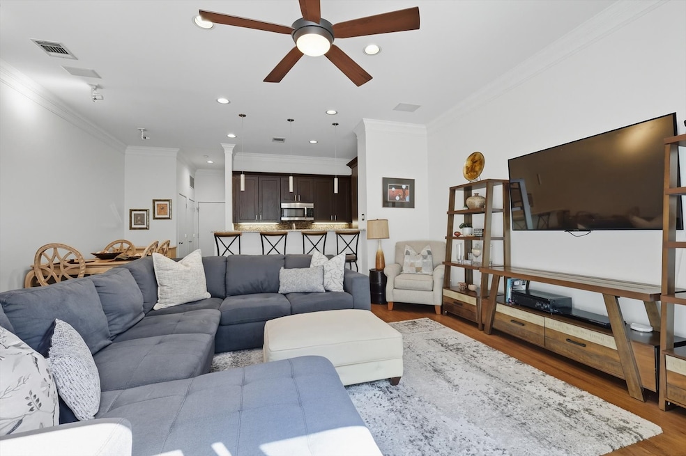 Living room with crown molding, wood finished floors, recessed lighting, and ceiling fan