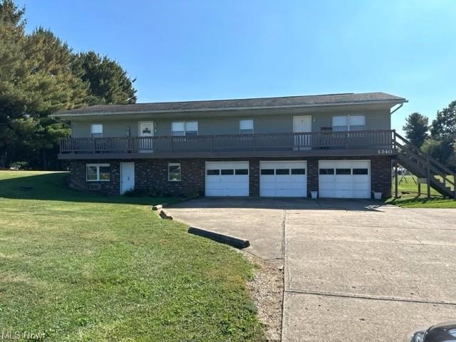 View of front of home with a wooden deck, a front yard, and a garage