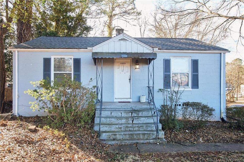 Bungalow-style home with concrete block siding, roof with shingles, and a chimney