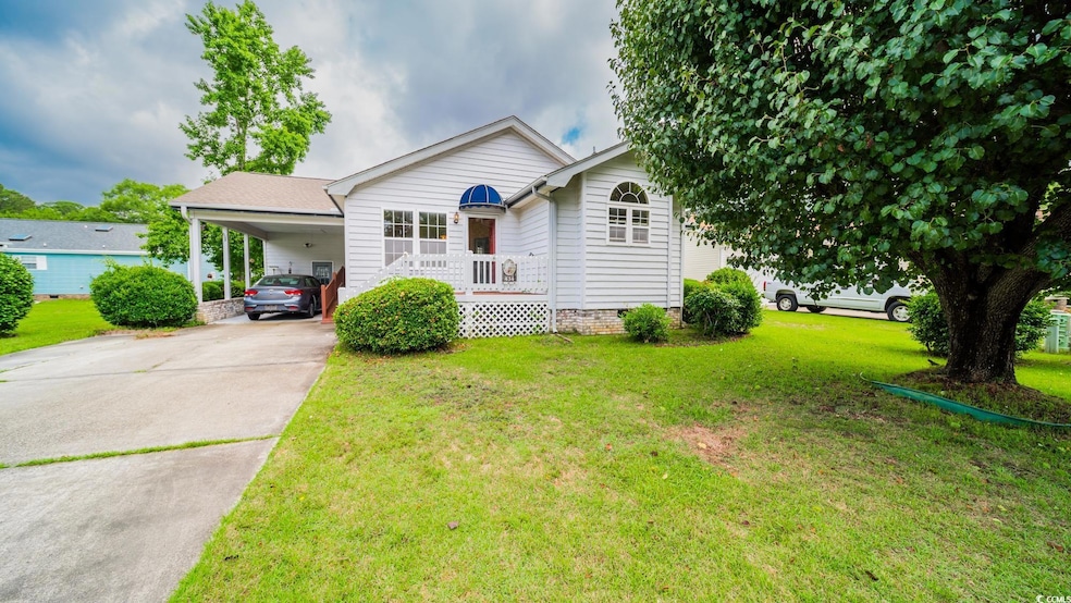 View of front of house with concrete driveway, a carport, a front yard, and crawl space