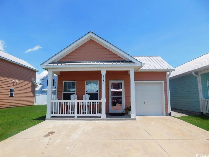 View of front of home with covered porch, concrete driveway, and metal roof