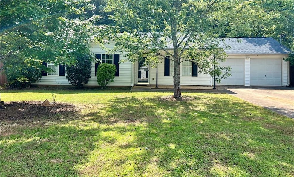 Front view of property with 2 car garage, driveway, and a front lawn