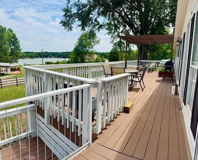 Deck with outdoor dining space and a water view