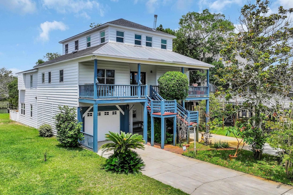 Coastal home featuring a front lawn, covered porch, concrete driveway, and stairway
