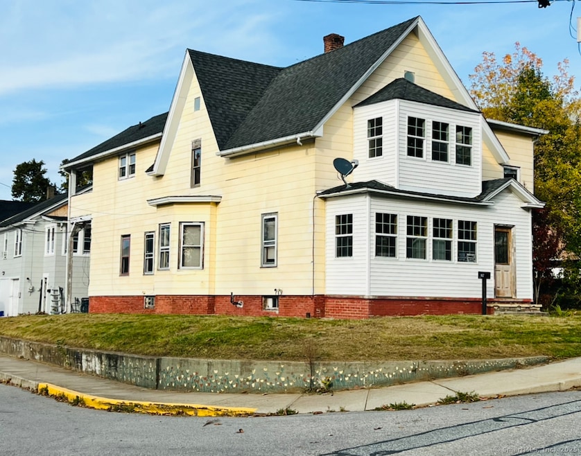 Yellow main building with 3 units inside, and grey 3 bay detached garage behind yellow building has a 2-bedroom unit above.