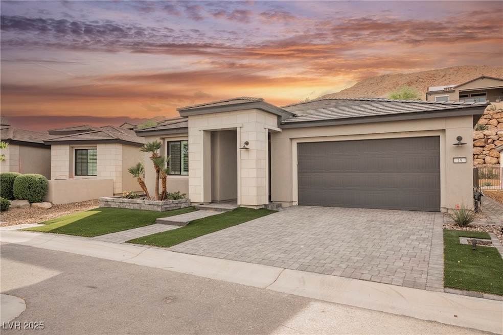 Prairie-style house with decorative driveway, a garage, and stucco siding