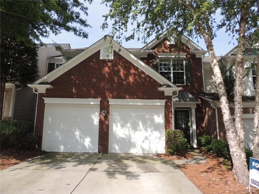 Traditional home with driveway, brick siding, and a garage
